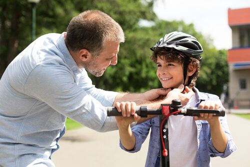 אב חובש קסדה לבנו שרוכב על סקוטר לילדים